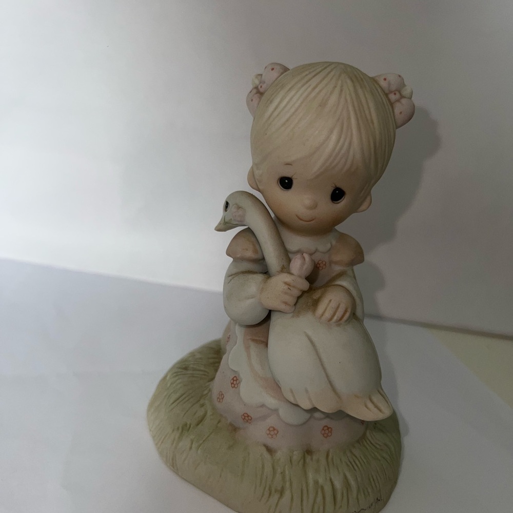 Precious Moments figurine "God Is Love," featuring a girl holding a goose
